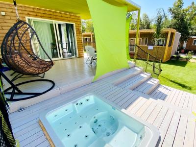 Terrasse mit Whirlpool, Hängesessel und grünem Sonnensegel.