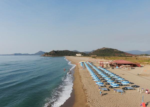 Plage paisible avec des parasols bleus et une mer calme, vue panoramique.