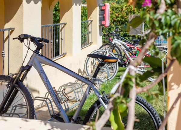 Bicycles parked in an outdoor bike rack on a sunny day.