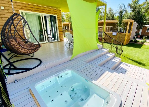 Terrasse mit Whirlpool, Hängesessel und grünem Sonnensegel.