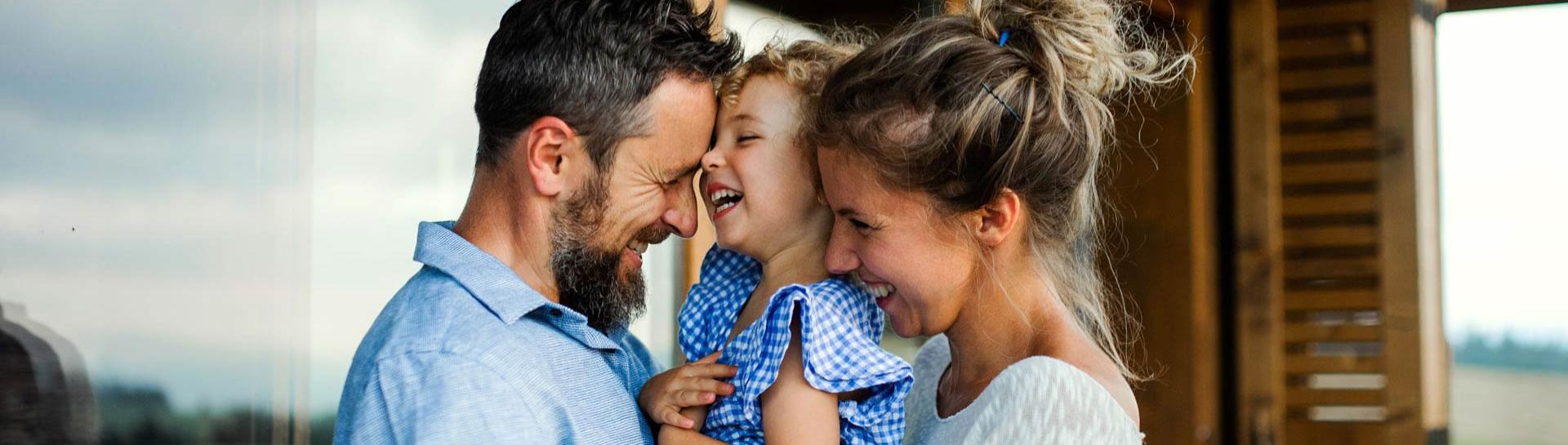Famille heureuse s'embrassant et riant ensemble en plein air.