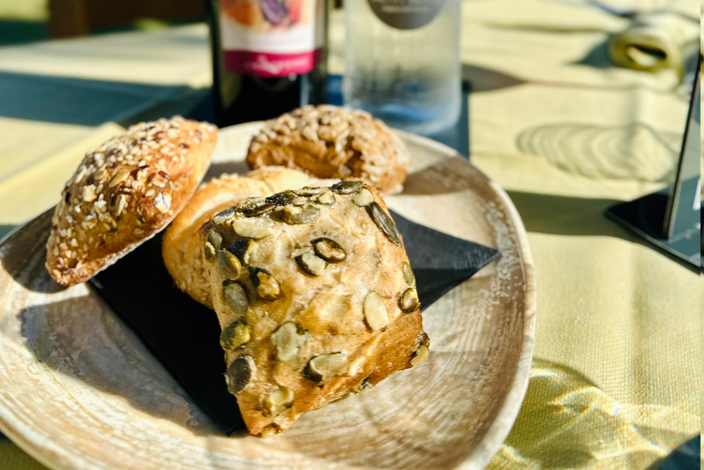 Pain assorti avec des graines sur une assiette, bouteille en arrière-plan.