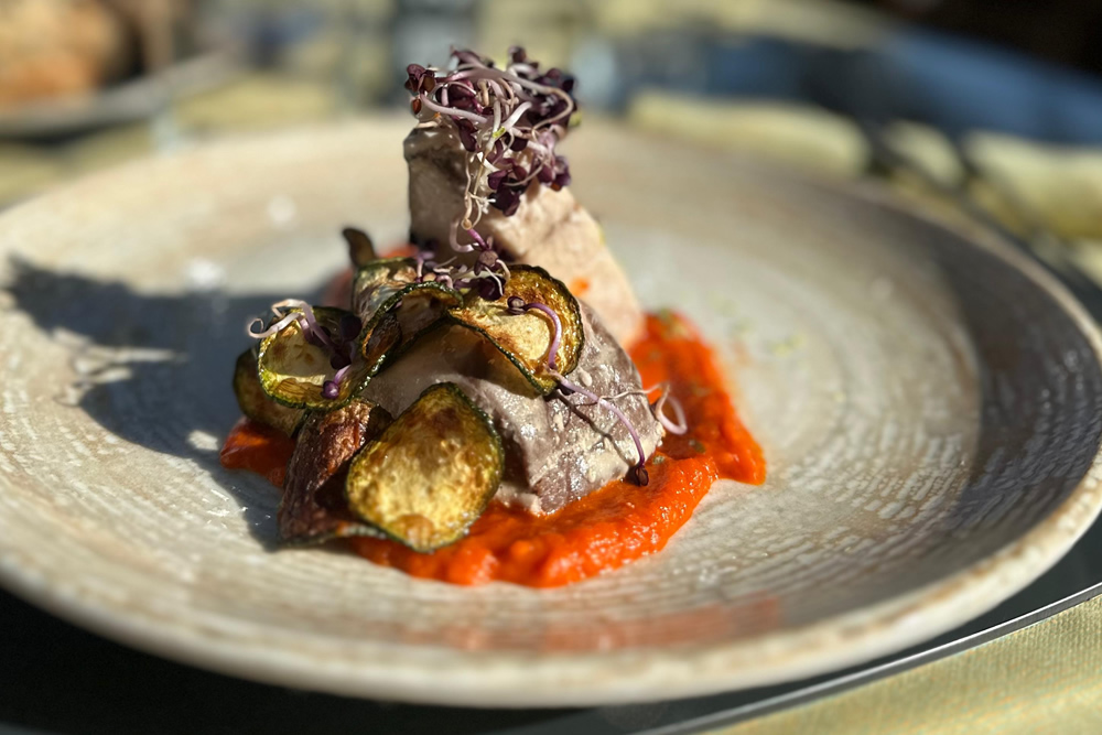 Plat gourmet avec viande, légumes grillés et sauce tomate.