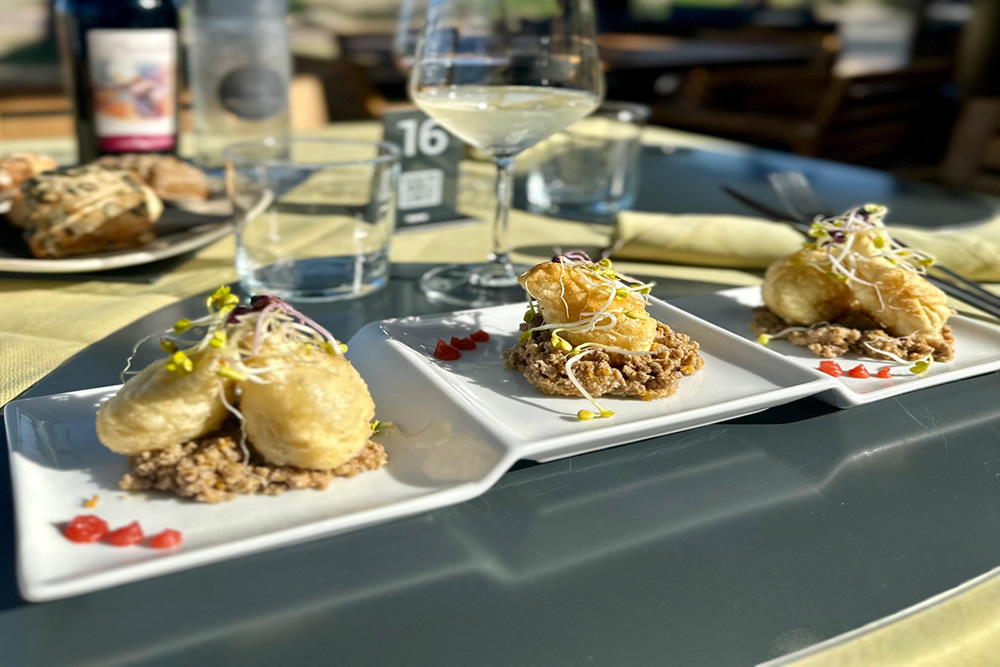Plat gastronomique avec croquettes sur lit de céréales et germes.