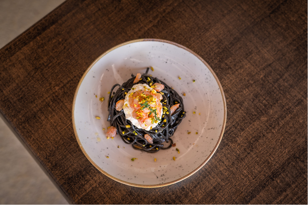 Squid ink spaghetti with shrimp and pistachio crumbs.